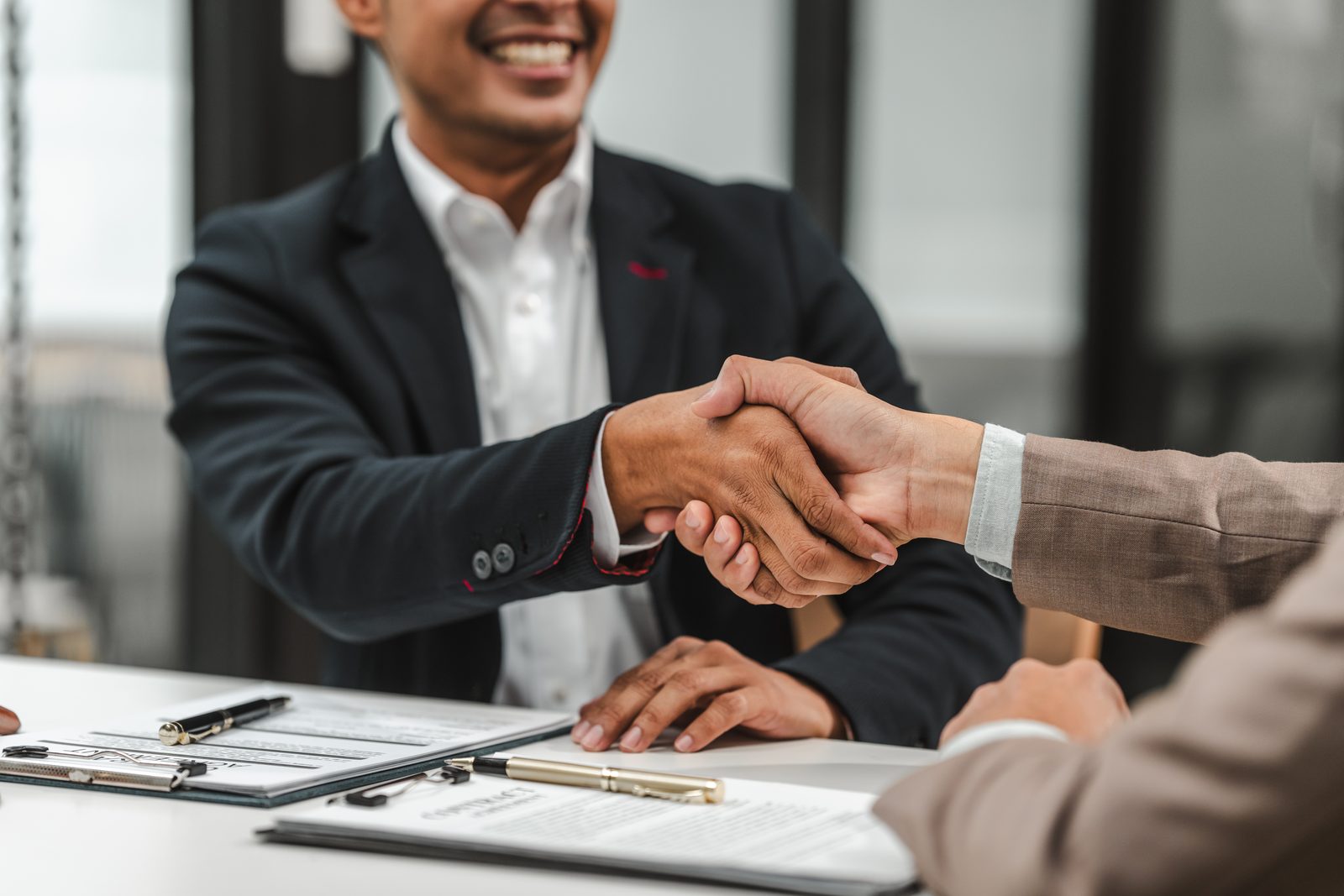 Car accident lawyer shaking hands with a client across a desk after reviewing a claim